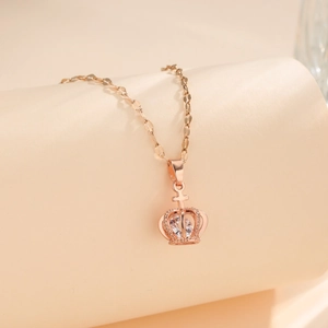 Rose gold crown pendant necklace with sparkling zircon stone on a soft beige background
