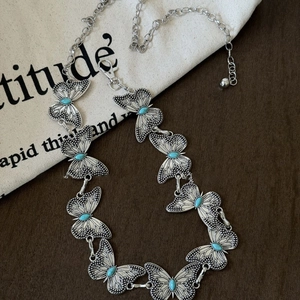 Bohemian silver butterfly waist chain with turquoise beads on a rustic wooden background