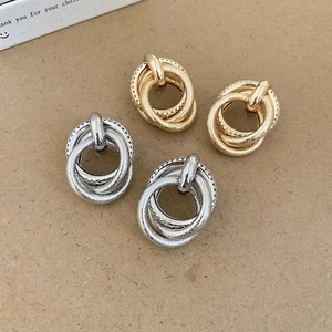 Detailed close-up of multilayered gold and silver intertwined knot earrings on paper