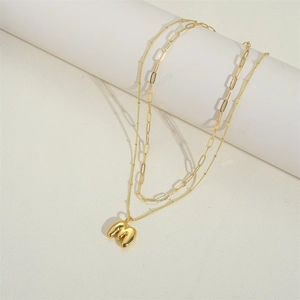 Detailed shot of a gold double-layer necklace with an M-letter pendant on white stands