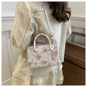Detail of a creamy white PU leather crossbody bag featuring delicate pink butterfly prints