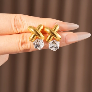Close-up of vintage gold cross earrings featuring a dangling cubic zirconia stone