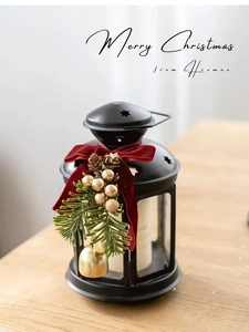 Black metal Christmas lantern with red velvet bow and pine needles on wooden surface