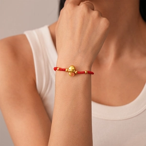 Detailed shot of red braided bracelet with golden lucky cat pendant and Fu character
