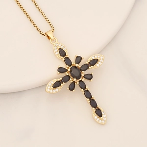 Macro shot of 18K gold cross pendant featuring black oval gem and white zircon accents