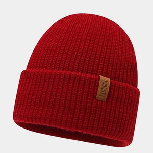Close-up of red ribbed knit beanie featuring a brown leather patch and woven texture