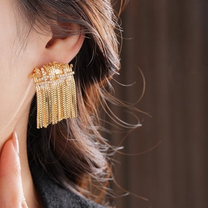Gros plan d'élégantes boucles d'oreilles dorées à glands portées par un mannequin