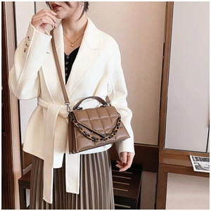 Brown quilted handbag detail with thick acrylic chain and long shoulder strap on model