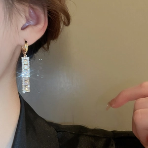 Detail of square zircon hollow earrings with shimmering gold finish and pavé stones