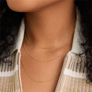 Close-up of triple-layered golden minimalist S925 silver necklace on model's neck