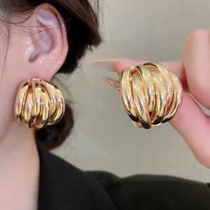Macro detail of gold chunky layered textured earrings showcasing a high-gloss metallic finish