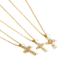 Three gold stainless steel cross necklaces with sparkling cubic zirconia on white background