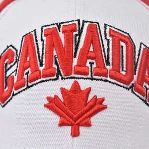 Macro shot of red Canada embroidery and maple leaf on a white cotton baseball cap