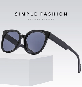 Minimalist black round frame sunglasses displayed on a white pedestal in a studio