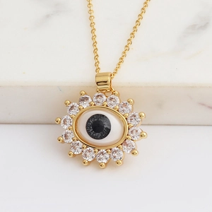 Detailed close-up of gold evil eye pendant with clear zircons on an O-shaped chain