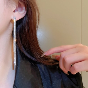 Close-up of long silver tassel earrings with zircon crystals worn by a model