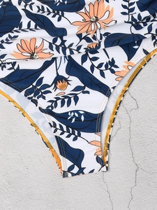 Nahaufnahme der Bikinihose mit tropischem Blumenprint und orangefarbenen Kontrastnähten