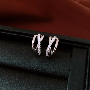 Close-up of silver crisscross hoop earrings with cubic zirconia in a leather jewelry box