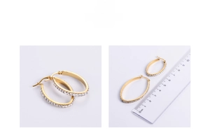 Detail view of gold titanium oval hoop earrings with crystals and size ruler guide