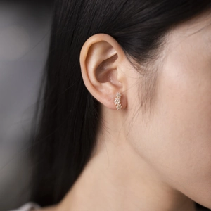 Close-up of elegant gold flower zircon stud earrings worn on a model earlobe