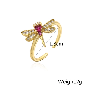 Macro detail of gold-plated dragonfly open ring featuring red and white zircon stones