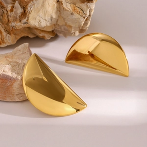 Macro detail of golden crescent earrings on natural stone background with soft shadows