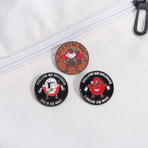 Close-up of three Ugandan Knuckles enamel pins with Mandalorian helmet on white canvas bag