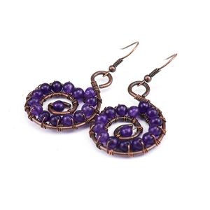 Detailed macro view of handmade copper wire-wrapped earrings with purple amethyst beads