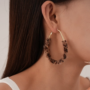 Close-up of stylish leopard print plush hoop earrings on a model for autumn winter