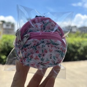 Close-up of a floral mini backpack coin purse with pink dual zippers in clear packaging