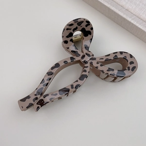 Detail of leopard print hair claw clip featuring a unique bow shape and gold metal spring