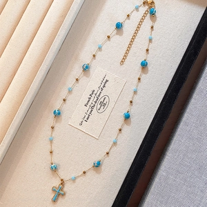 Blue stone beaded cross pendant necklace in a beige jewelry display box for women