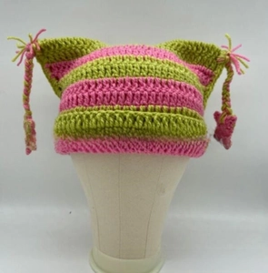 Close-up of pink and green striped cat ear beanie with braided tassels and stars