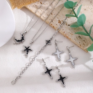 Detailed flat lay of silver necklaces with black moon and star pendants on white fabric