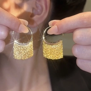 Elegant gold fringe earrings with metallic tassels and sparkling finish on model