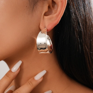 Close-up of polished silver C-shaped metal stud earring on model with high glossy finish