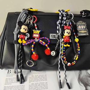 Dettaglio dei ciondoli Topolino e Toy Story appesi a una borsa di pelle nera
