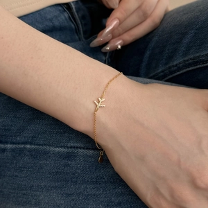 Detail of a delicate gold-toned bracelet featuring a sparkling airplane charm on the wrist
