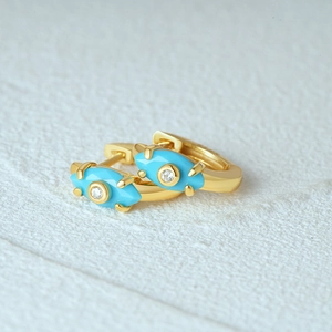 Detailed macro view of S925 silver gold-plated devil eye earrings with blue gems