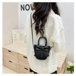 Detailed back view of a chic black leather crossbody bag with a decorative bow on a model