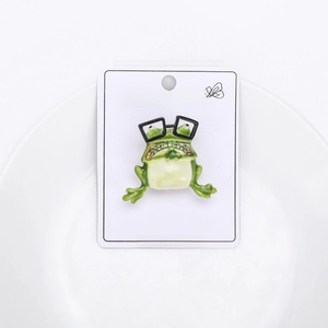 Macro shot of fashion frog brooch with green enamel body and sparkling crystal rhinestones