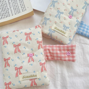 Close-up of fabric book cover with cute bow, floral patterns and brand embroidery