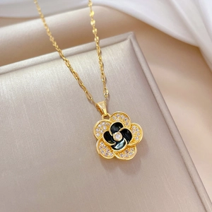 Detailed view of camellia flower pendant with black and white petals and crystal inlay