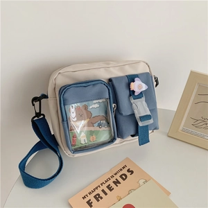 Detail of color-block canvas crossbody bag featuring PVC pocket and cartoon bear illustration