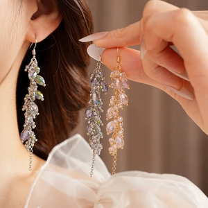 Detail view of long tassel earrings with faceted crystal beads on model with mesh background