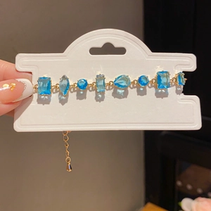 Detail of gold bracelet with mixed-cut light blue gemstones and adjustable clasp