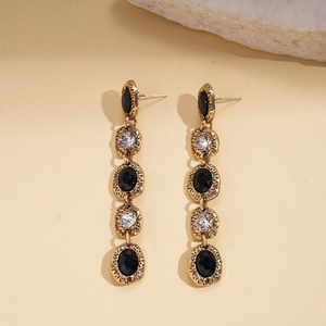 Detail of vintage gold tassel earrings with hammered texture and black and white stones