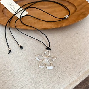 Detail of silver flower pendant with heart center on adjustable black cord necklace
