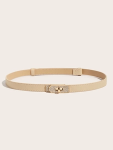 Close-up of beige slim belt featuring a gold turn-lock buckle with micro rhinestones