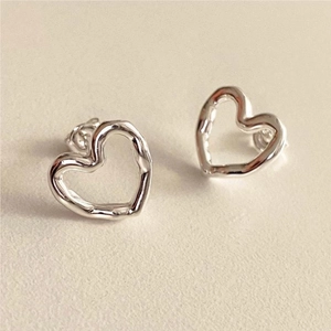 Macro shot of 925 sterling silver hollow heart studs with unique organic liquid metal texture
